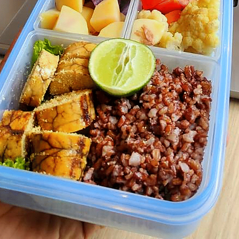 Close-up of tempeh, red rice and lime in a Fit Food Bali bento box